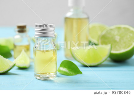 Lime essential oil and cut citrus fruits on light blue wooden table. Space for text 95780846