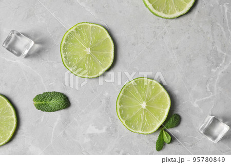 Flat lay composition with slices of fresh juicy limes on marble table Flat lay composition with slices of fresh juicy limes on marble table 95780849