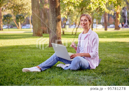 Businesswoman sitting grass summer park using laptop  95781278
