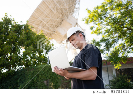 Engineer looking earth based astronomical radio telescope Engineer looking earth based astronomical radio telescope 95781315
