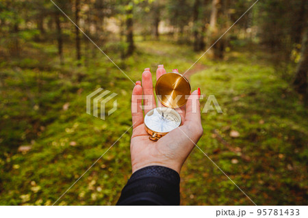 Hand with compass in forest terrain. POV Travel concept 95781433