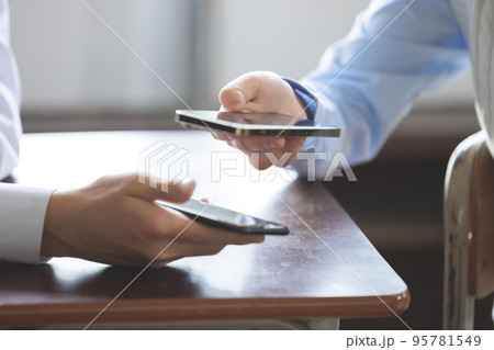 スマホを操作する学生二人 95781549