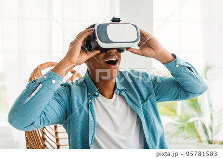 Happy inspired young black man in VR glasses with open mouth enjoy online virtual reality game Happy inspired young black man in VR glasses with open mouth enjoy online virtual reality game 95781583