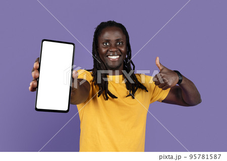 Cheerful cool black guy showing cell phone and thumb up Cheerful cool black guy showing cell phone and thumb up 95781587