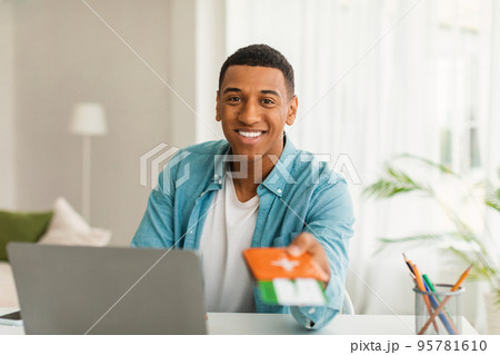 Glad handsome young african american man in casual with computer gives passport and air tickets to client Glad handsome young african american man in casual with computer gives passport and air tickets to client 95781610