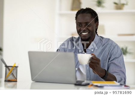 Distance Work. Happy Black Freelancer Guy Drinking Coffee And Using Laptop 95781690