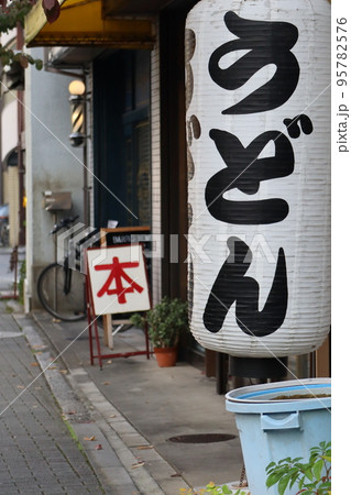 うどんと書かれた提灯と本の看板のある路地の町並みの風景 うどんと書かれた提灯と本の看板のある路地の町並みの風景 95782576