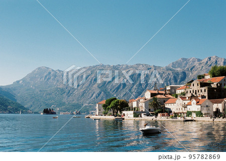 Embankment of Perast with old stone houses against the backdrop of mountains 95782869