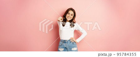 Its you, congrats. Beautiful woman with enthusiastic smile, pointing fingers at camera, congratulating, inviting people, choosing, standing over pink background Its you, congrats. Beautiful woman with enthusiastic smile, pointing fingers at camera, congratulating, inviting people, choosing, standing over pink background 95784355