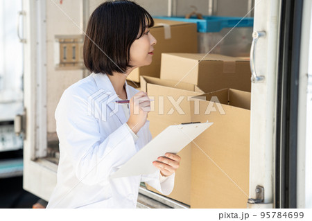 トラックの荷物をチェックする白衣の女性 95784699