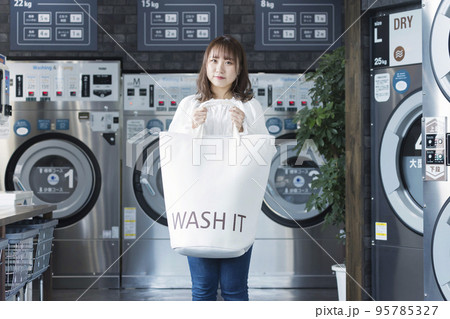 コインランドリーでランドリーバッグを持つ若い女性 コインランドリーでランドリーバッグを持つ若い女性 95785327