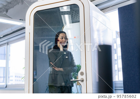 個室ワークブースで電話をかけるビジネスウーマン 95785602
