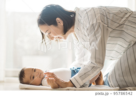 タオルに横になる赤ちゃんとあやすママ 95786542
