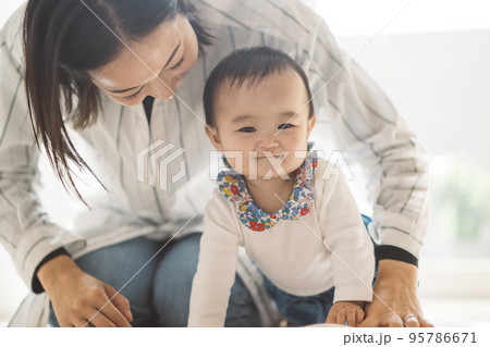 立ち上がろうとする赤ちゃんと、あやすママ 立ち上がろうとする赤ちゃんと、あやすママ 95786671