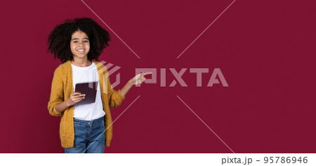 Happy black child with digital pad pointing at copy space 95786946