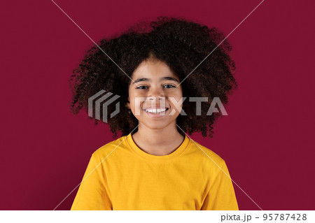 Portrait of smiling african american kid girl on burgundy background 95787428