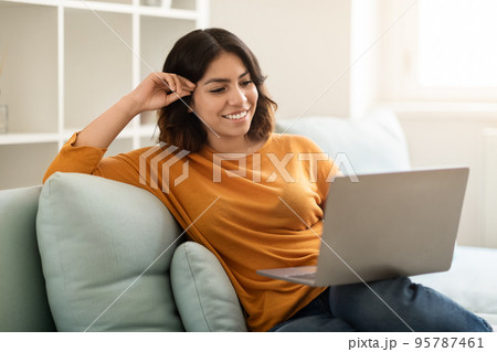 Happy Young Middle Eastern Woman Resting On Couch With Laptop 95787461