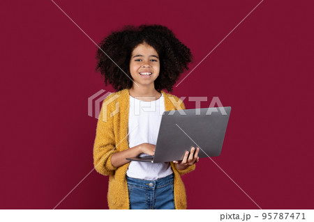 Cheerful black girl schooler holding laptop, colorful background 95787471