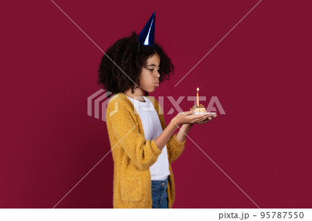 Adorable black girl having birthday party, blowing candle 95787550