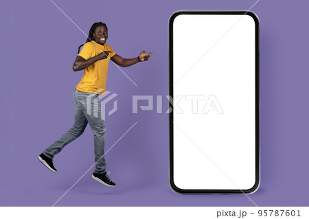 Emotional black guy jumping by huge smartphone, mockup Emotional black guy jumping by huge smartphone, mockup 95787601