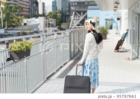 スーツケースを引いて名古屋観光をする若い女性 振り返り 95787661