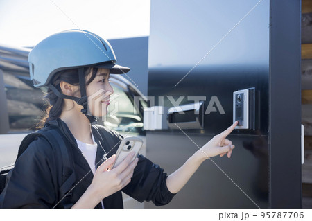 フードデリバリーイメージ インターホンのボタンを押す若い女性  シェアデリ フードデリバリーイメージ インターホンのボタンを押す若い女性  シェアデリ 95787706