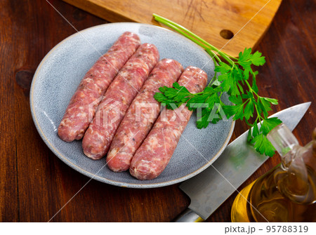 Plate with raw Catalan sausages botifarra and greens prepared for cooking Plate with raw Catalan sausages botifarra and greens prepared for cooking 95788319