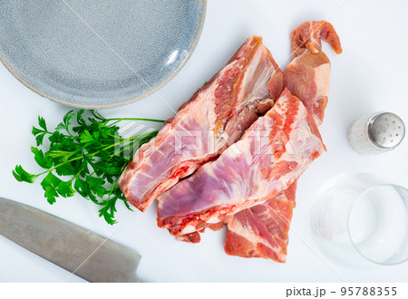Pieces of fresh uncooked pork ribs with parsley on wooden table 95788355