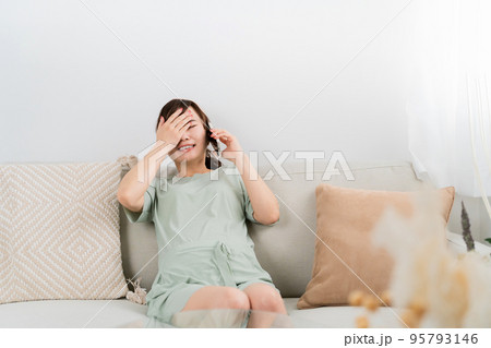 陣痛がきて電話するアジア人女性（妊婦・出産・マタニティ） 95793146