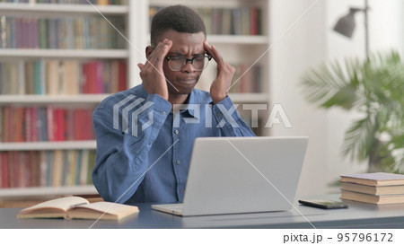 Young African Man having Headache while Working on Laptop Young African Man having Headache while Working on Laptop 95796172