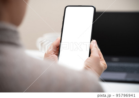 Cropped shot of businesswoman looking at blank screen smartphone in modern office room. woman hand holding phone with white screen in office. woman using cell phone at workplace 95796941