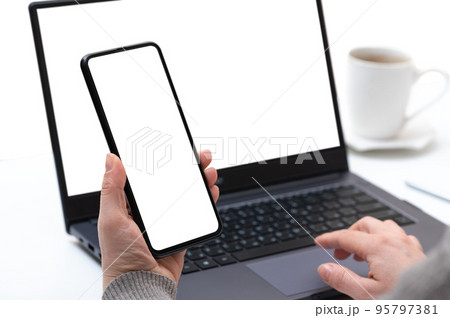 Mockup device. businesswoman using smartphone and notebook. female hands typing on laptop keyboard with blank white screen, cell phone and laptop use at same time Mockup device. businesswoman using smartphone and notebook. female hands typing on laptop keyboard with blank white screen, cell phone and laptop use at same time 95797381
