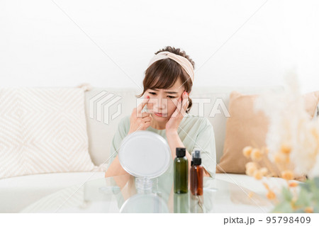 鏡を見て肌に悩む女性（目・目尻） 95798409