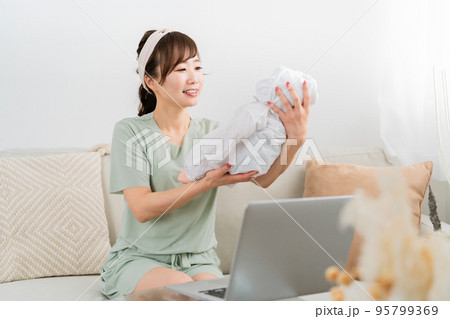 テレワークをしながら赤ちゃんをあやす女性 テレワークをしながら赤ちゃんをあやす女性 95799369