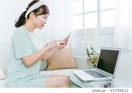 家でパソコンとスマホを使う日本人女性（パジャマ・テレワーク） 95799622