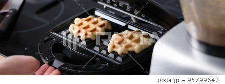 Cooking waffles in waffle iron at home closeup Cooking waffles in waffle iron at home closeup 95799642