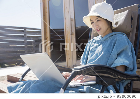 サウナ外気浴をしながらパソコンを操作する若い女性 サウナ外気浴をしながらパソコンを操作する若い女性 95800090