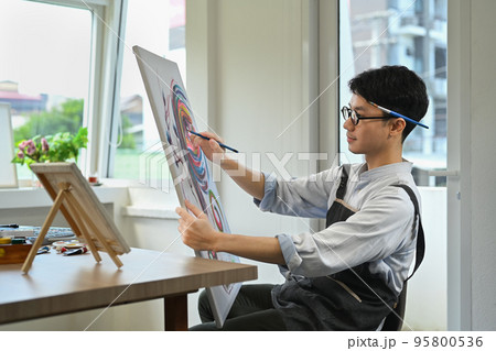 Pleasant man painting picture with watercolor at cozy home studio. Art, creative hobby and leisure activity concept 95800536