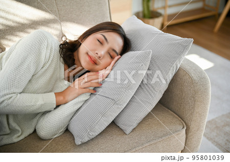 Beautiful, calm and peaceful Asian woman napping or sleeping on couch in her living room 95801039