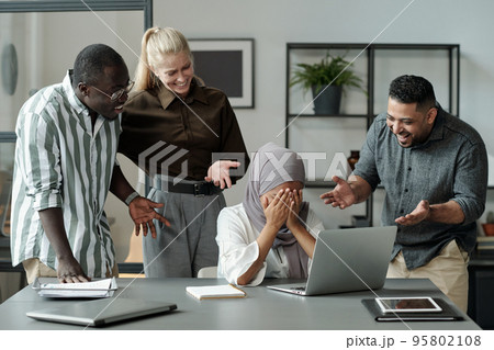 Group of cruel young multicultural classmates making fun of girl in hijab 95802108