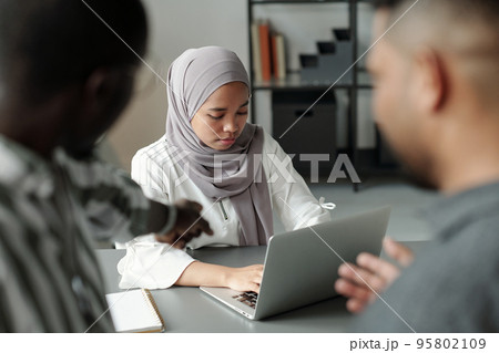 Young Muslim female student networking while two men pointing at her 95802109