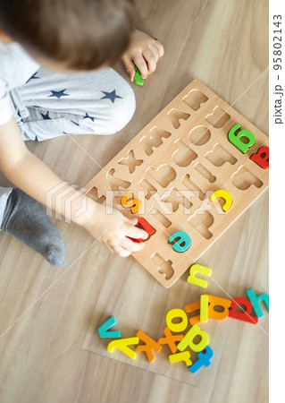 Male kid playing with wooden eco friendly alphabet letters board on table top view intellectual game Male kid playing with wooden eco friendly alphabet letters board on table top view intellectual game 95802143