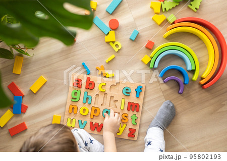 Male kid playing with wooden eco friendly alphabet letters board on table top view intellectual game 95802193