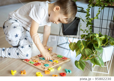 Male kid playing with wooden eco friendly alphabet letters board on table top view intellectual game 95802230