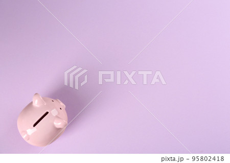 Piggy bank on violet background, top view. Space for text 95802418