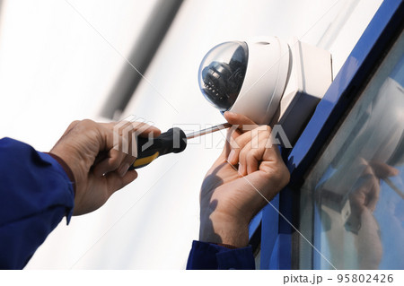 Technician installing CCTV camera on wall outdoors, closeup 95802426
