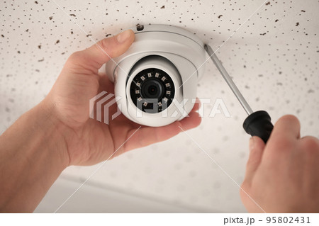 Technician installing CCTV camera on ceiling indoors, closeup 95802431