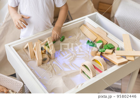 Cute male kid playing with sensory box kinetic sand table Montessori material wooden ecology toys Cute male kid playing with sensory box kinetic sand table Montessori material wooden ecology toys 95802446