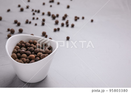 Black peppercorns in bowl on grey table. Space for text Black peppercorns in bowl on grey table. Space for text 95803380