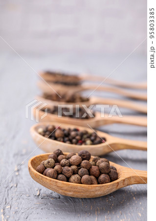 Spoons with peppercorns on grey wooden table, closeup Spoons with peppercorns on grey wooden table, closeup 95803385